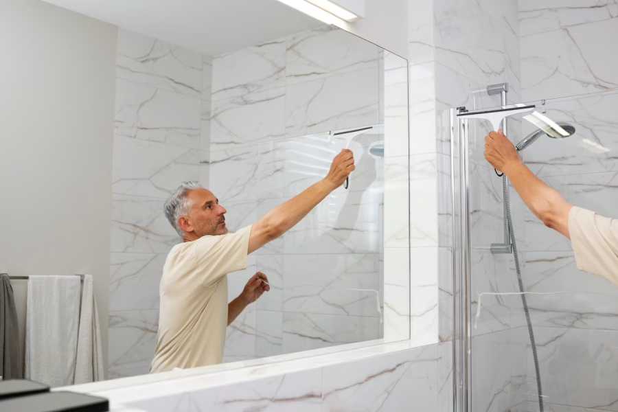 Man wiping on the mirror of a bathroom
